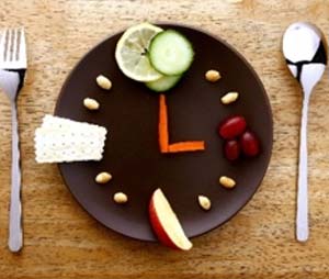 A plate of fruit and nuts arranged to mimic an analog clock