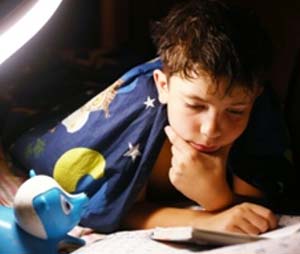 A young child reading by lamp light before bed
