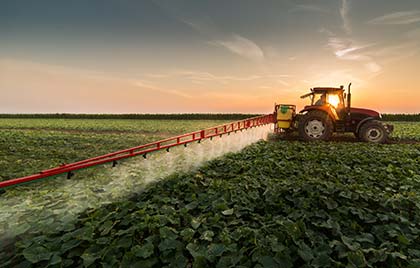 Image of tractor spreading pesticides on a field