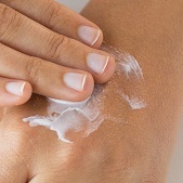 Woman's hand applying a cream to skin