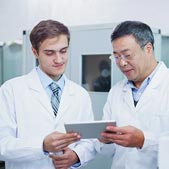 Two male scientists reviewing data on a tablet