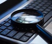 Magnifying glass resting on a computer keyboard