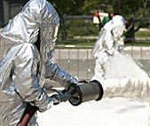 man in a full protective suit spraying a chemical