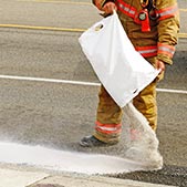 Fireman pouring absorbent on oil spilled from a wreck