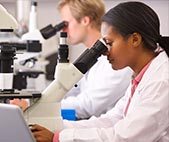 Male and female scientists using microscopes in a science lab