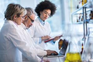 Three scientists working at a laboratory bench.