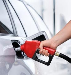Woman pumping gasoline into a silver car